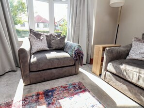 A living room with a sofa, a rug, and a lamp. - 44 Love Lane (Whitby)