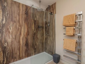 Ein modernes Badezimmer mit Duschkabine aus Glas, einer Badewanne und einem Handtuchhalter mit mehreren Handtüchern.