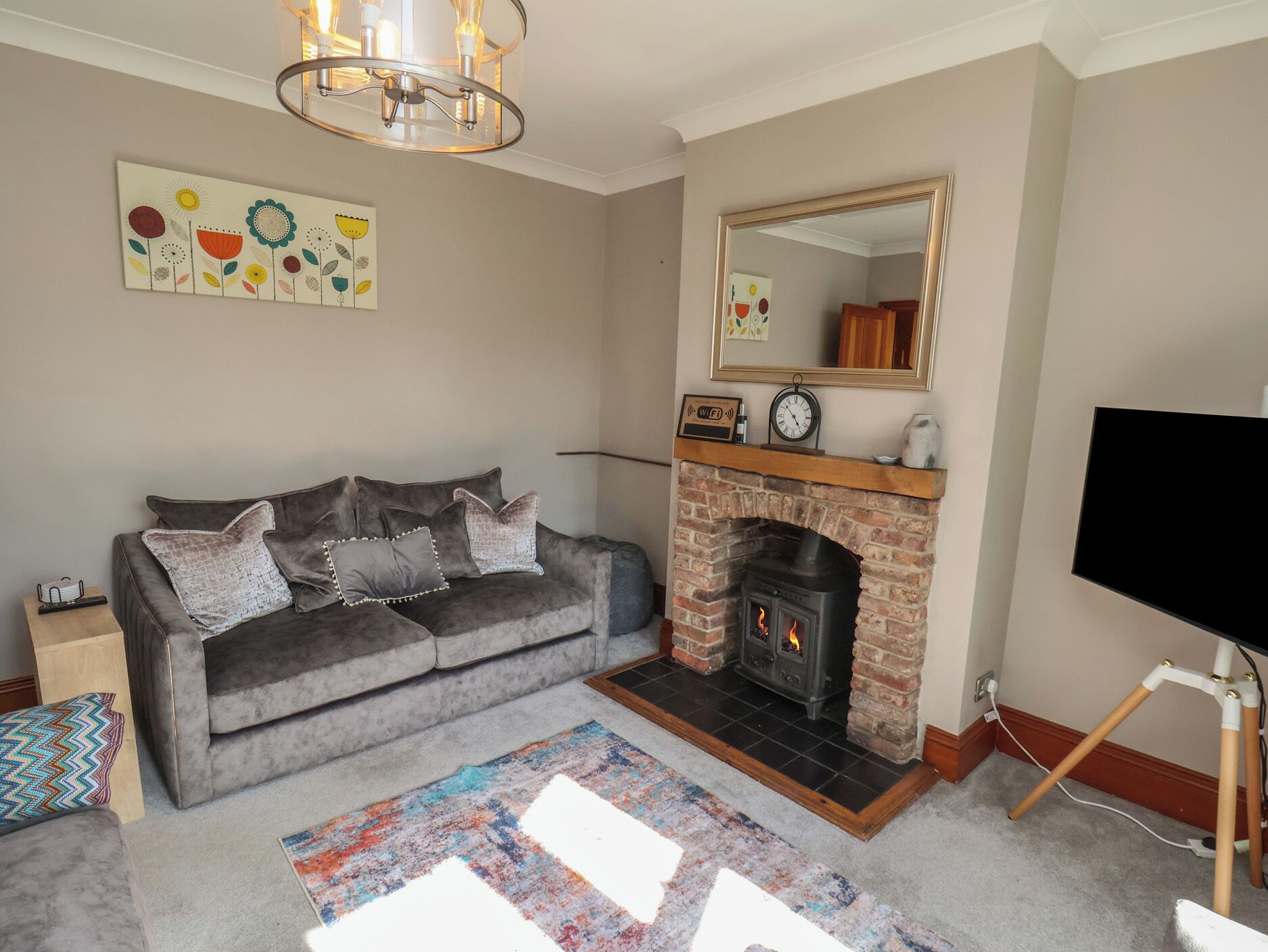 A living room with a sofa, fireplace, TV, and artwork on the wall.
