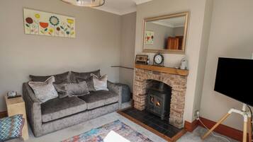A living room with a sofa, fireplace, TV, and artwork on the wall.