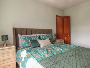 A bedroom with a bed, a nightstand, a lamp, and a wooden door. - 44 Love Lane (Whitby)