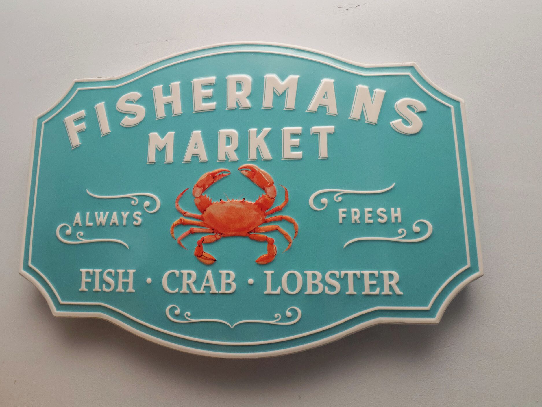 Señal para Fisherman's Market con una ilustración de cangrejo y referencias a pescado, cangrejo y langosta.