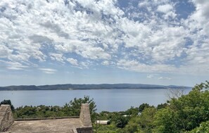 Eine Küstenlandschaft mit blauem Himmel, einem Gewässer und sanften Hügeln im Hintergrund.
