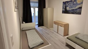 Ein Schlafzimmer mit einem Bett, einem Schreibtisch, einem Kleiderschrank und einem Bild an der Wand.