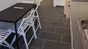 Eine moderne Küche mit weißen Schränken, einer schwarzen Arbeitsplatte und einem gefliesten Boden.