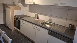 Eine moderne Küche mit weißen Schränken, einer Edelstahl-Spüle und einem Geschirrspüler.