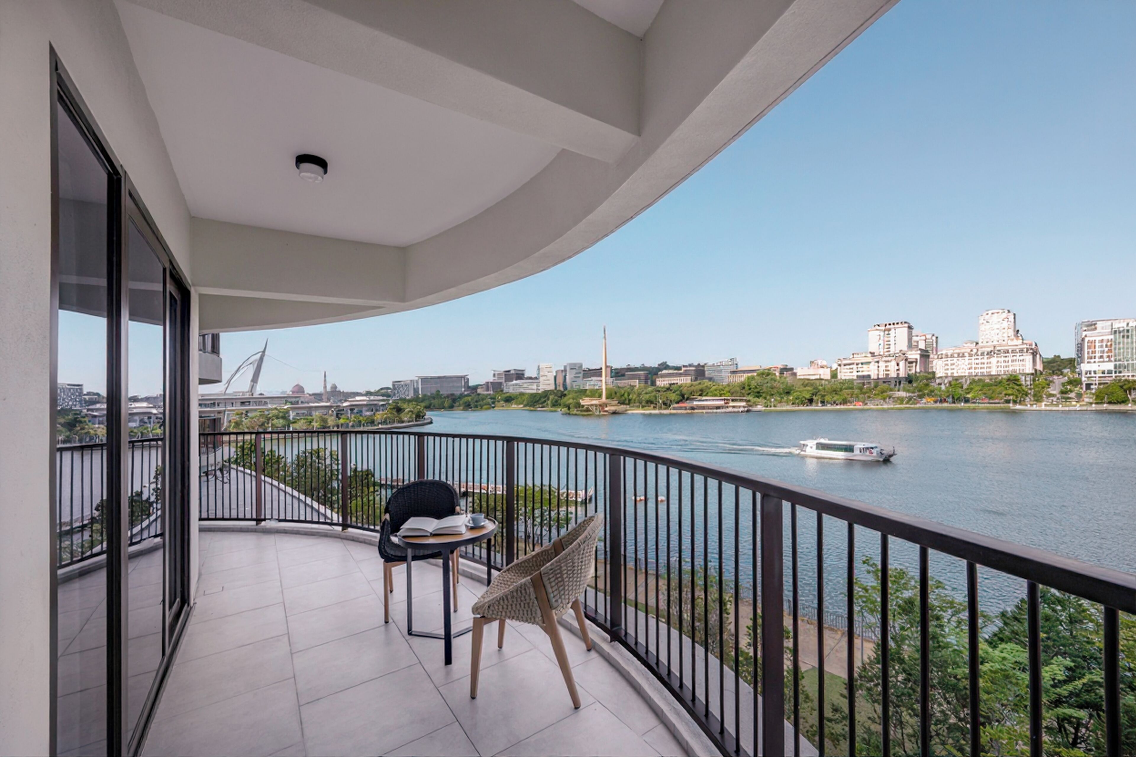 Un balcón con vista a un río, un barco y un paisaje urbano al fondo.