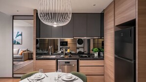 A modern kitchen with a dining area, stainless steel appliances, and a unique pendant light.
