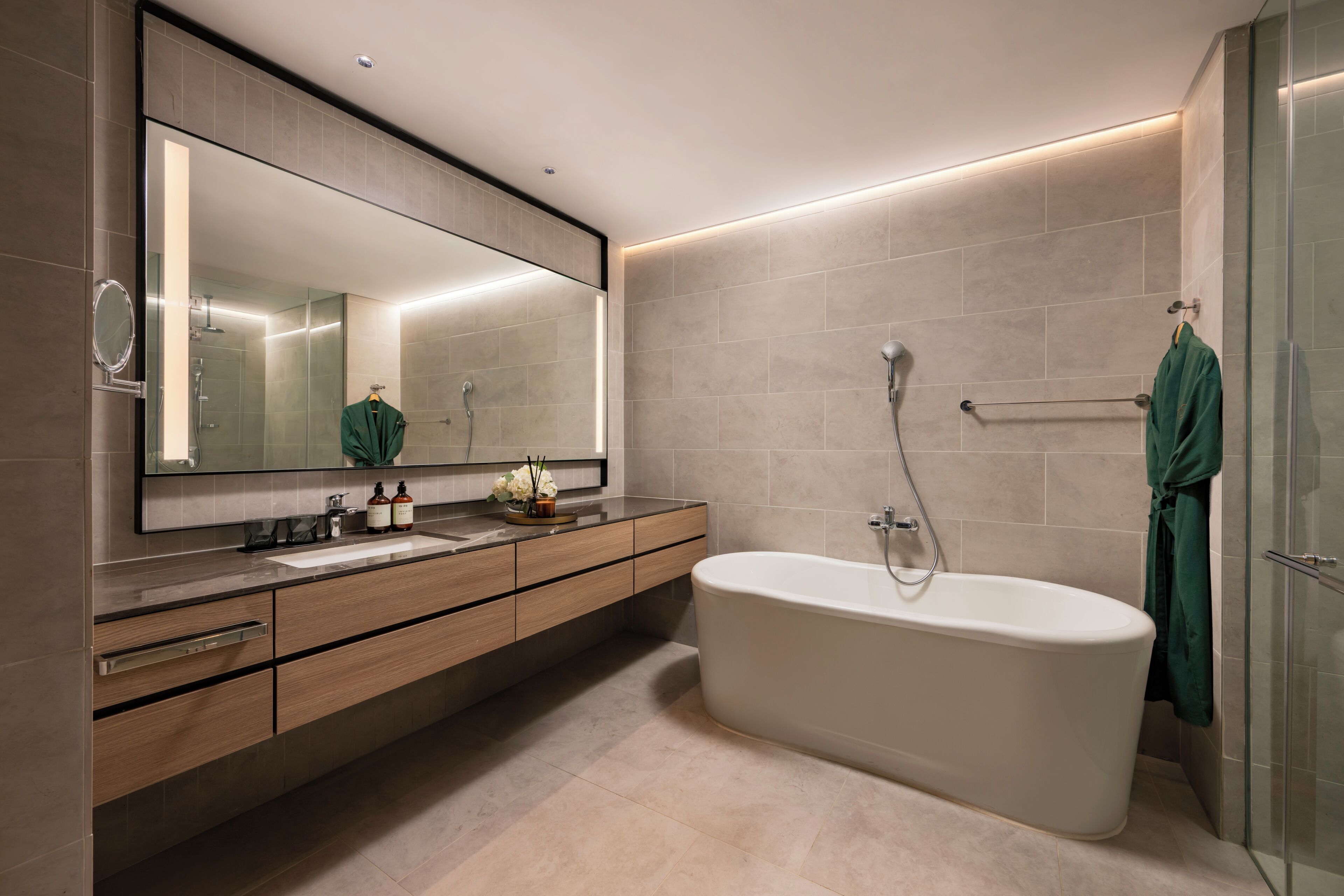Un baño moderno con una bañera independiente, un espejo grande y un tocador con lavamanos.