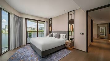 Quarto de hotel moderno com cama grande, mesa de cabeceira, vista da cidade e varanda.