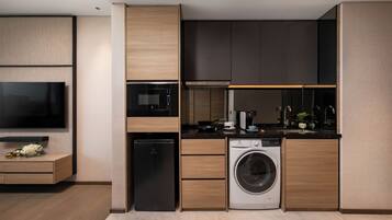 A modern kitchen with built-in appliances, a flat-screen TV, and a washing machine.