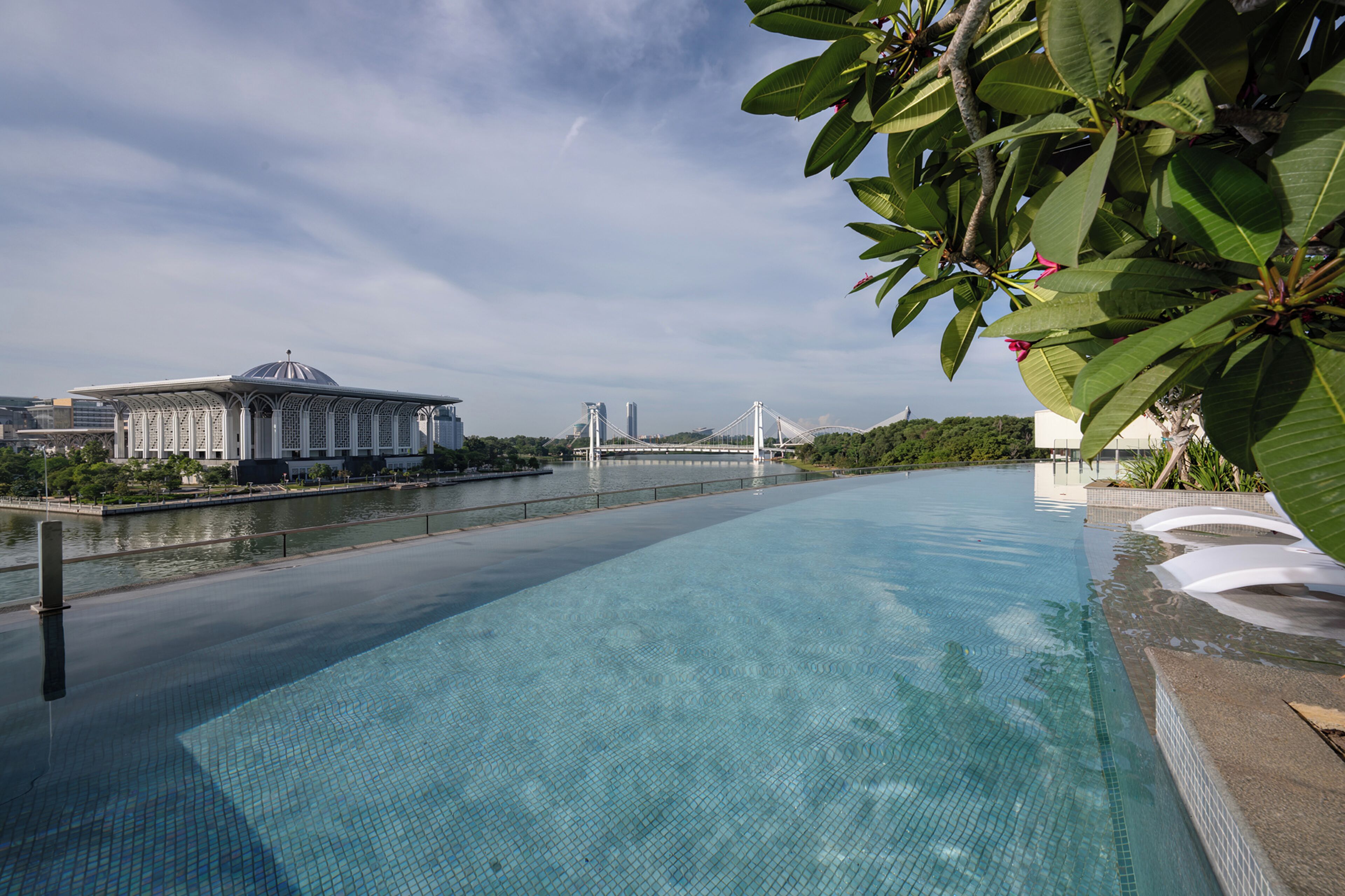A swimming pool with a view of a bridge and buildings in the background.