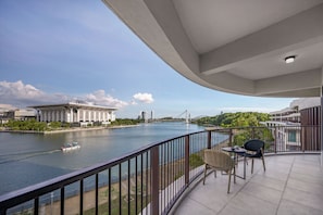 A balcony with a view of a river, a bridge, and a building with a dome.