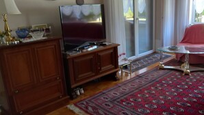 Ein Wohnzimmer mit Fernseher, Holzschrank, Glastisch und einem roten Sofa.