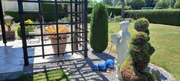 A garden with a metal gate, potted plants, a statue, and a well-maintained lawn.
