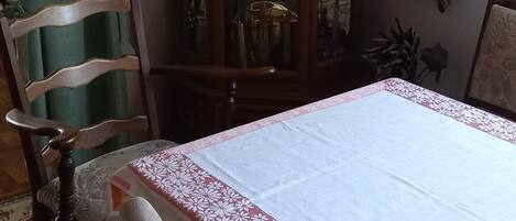 Un coin repas comprenant une table, des chaises, un buffet en bois et une lampe.