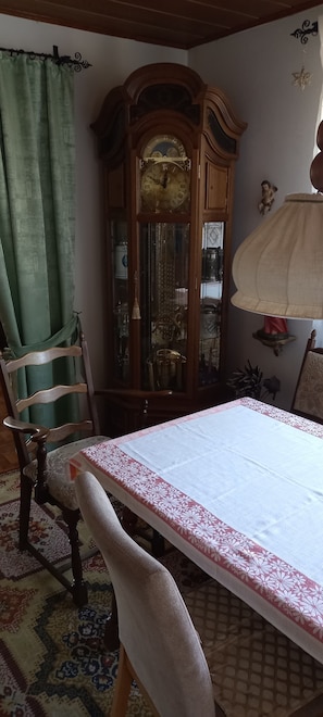 Et spiseområde med et bord, stole, et træskab og en lampe.