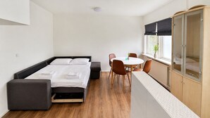 A modern room with a bed, a dining table, chairs, a cabinet, and a window with a view. - Modern Studio in Central Tórshavn (Tórshavn)