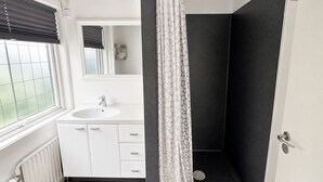 A bathroom with a white sink, mirror, and shower. - Modern Studio in Central Tórshavn (Tórshavn)