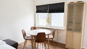 A room with a round table, four chairs, a cabinet, and a window with blinds. - Modern Studio in Central Tórshavn (Tórshavn)