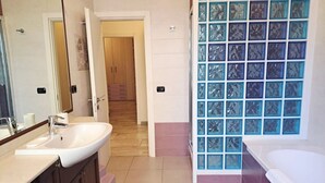 Un bagno con lavandino, specchio e cabina doccia in vetro.