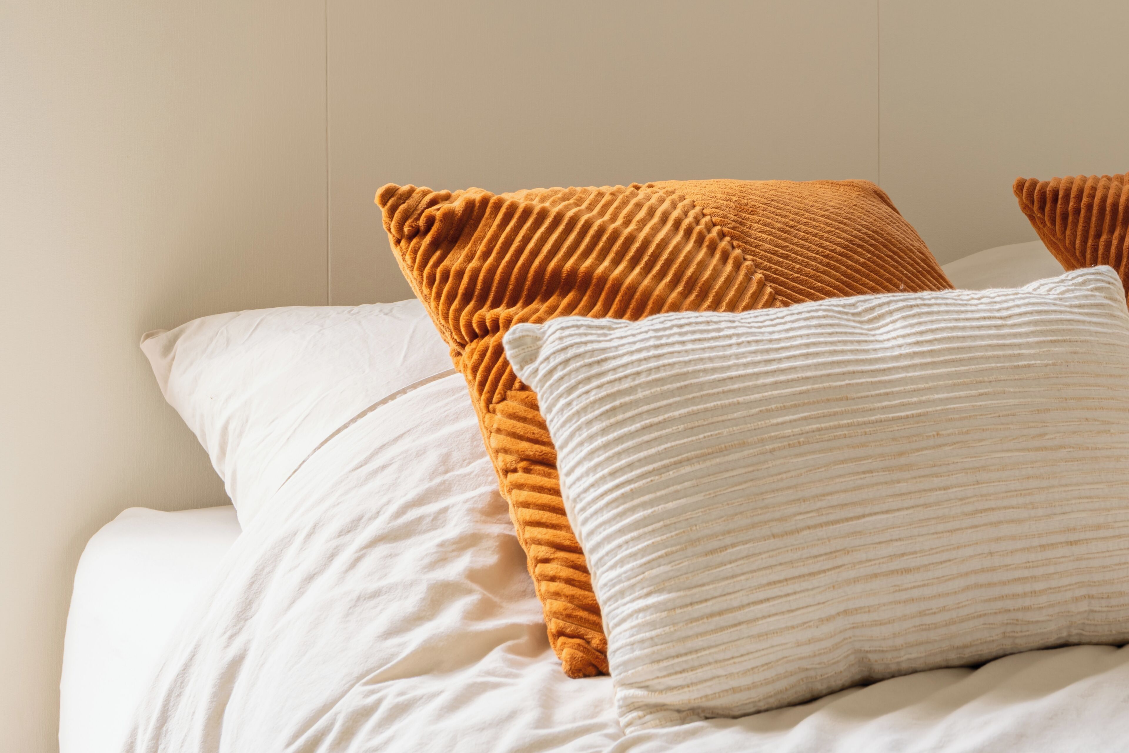 A bed with white and brown pillows.
