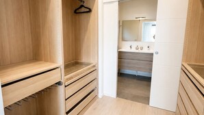 A walk-in closet with wooden shelving, a hanging rack, and a mirrored closet door. - Villa Between Sky & Paradise - Pool & Valley View (Montfuron)