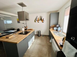 A modern kitchen with a central island, a built-in oven, and a sink. - Renovated family home with sea view, swimming pool and terrace, 10min walk from the beach (Carqueiranne)