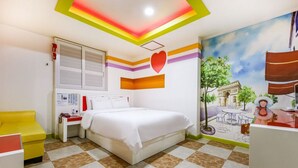 Una habitación de hotel con una cama, una silla amarilla, un escritorio, un calentador montado en la pared y un mural de un paisaje urbano.