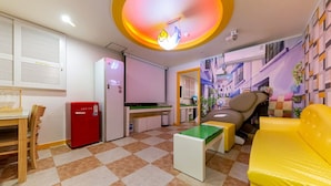 Un espacio habitable compacto con kitchenette, comedor, sofá y televisor.