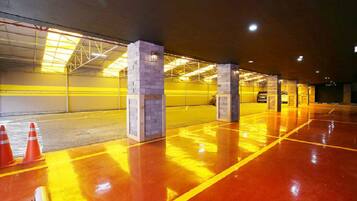 Een parkeergarage met gele lijnen, betonnen pilaren en oranje verkeerspalen.