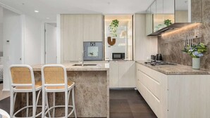A modern kitchen with a central island, white cabinetry, and a microwave. - LaneStay - Premium 2BR Retreat, Parking & Pool & Gym (Melbourne)