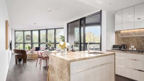 A modern kitchen with a large island, built-in appliances, and large windows offering a view of the outdoors. - LaneStay - 2BR Albert Park Views, Pool Gym Parking (Melbourne)