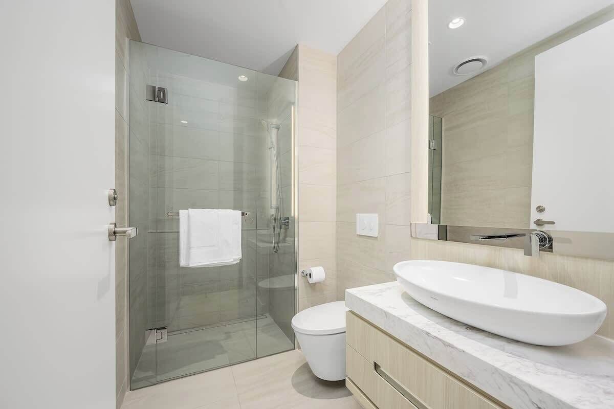 Un bagno moderno con doccia vetrata, lavandino bianco e uno specchio grande.