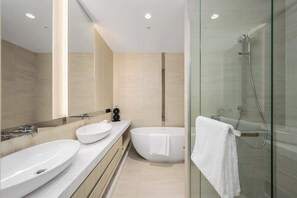 A modern bathroom with a glass shower enclosure, a freestanding bathtub, and a double sink vanity. - LaneStay - Lakeside Luxury with Pool, Gym, Parking (Melbourne)