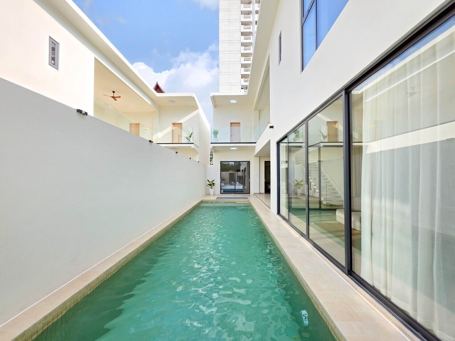 Um edifício moderno com piscina, portas de vidro e varanda.