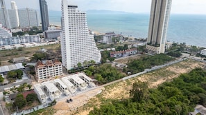 Et højt hotel med flere etager, udsigt til stranden og parkeringsplads.