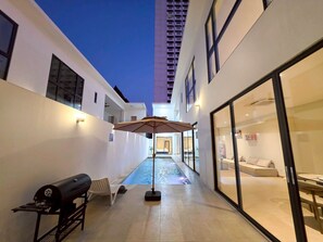 A modern building with a pool, outdoor seating, and a grill. - Seaview Pool Villa Jomtien KTV BBQ Beach (Muang Pattaya)
