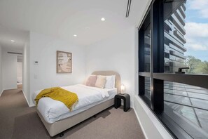 A modern bedroom with a bed, bedside table, and a window with a view of a building. - LaneStay - Luxury Living with Pool, Gym & Parking (Melbourne)
