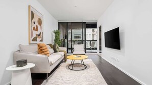 Een moderne woonkamer met een bank, een salontafel, een televisie en een groot raam.
