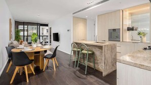 Een moderne keuken met een centraal eiland, donkere houten vloeren en een eethoek met een ronde tafel en stoelen.