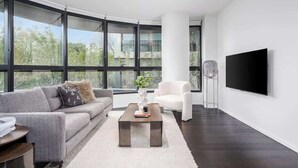 Ein modernes Wohnzimmer mit Sofa, Sesseln, Couchtisch und einem an der Wand montierten Flachbildfernseher.
