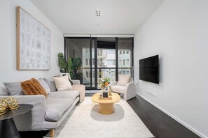 A modern living room with a sofa, coffee table, and TV. - LaneStay - Elevated 2B2B w Pool, Gym and Parking (Melbourne)