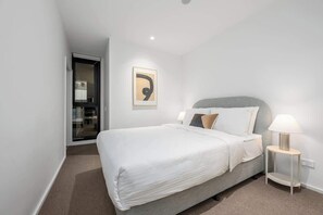 Una camera d'albergo moderna con un letto grande, un comodino con una lampada e un quadro appeso al muro.