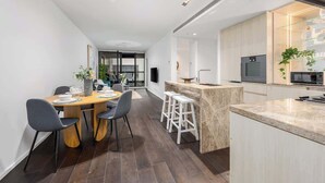 Una cocina moderna con una isla central, taburetes de bar y un comedor con sillas.