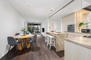 Una cocina moderna con una isla central, taburetes de bar y un comedor con sillas.