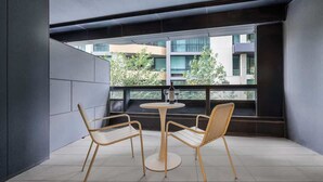 A balcony with two chairs and a table, a view of buildings and greenery, and a modern architectural style. - LaneStay - 2BR Refined Living, Pool & Gym & Parking (Melbourne)
