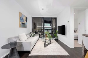A modern living room with a sofa, coffee table, and TV. - LaneStay - 2B2B Resort Living, Pool Gym Parking (Melbourne)