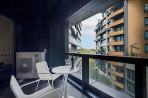 A balcony with a table, chairs, and a bottle of wine. - LaneStay - 2B2B Resort Living, Pool Gym Parking (Melbourne)