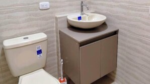 A bathroom with a toilet, sink, and cabinet. - Cozy apartment ideal for travelers, digital nomads, or families. (Bogotá)